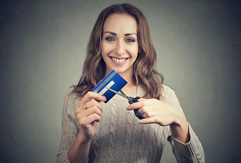 Kvinna klipper kreditkort - samla lån