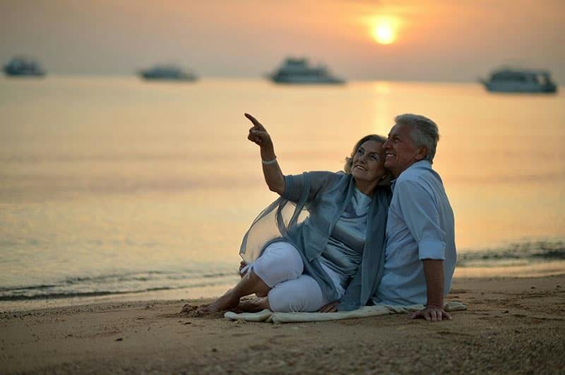 Vanhempi pariskunta rannalla auringonlaskussa 