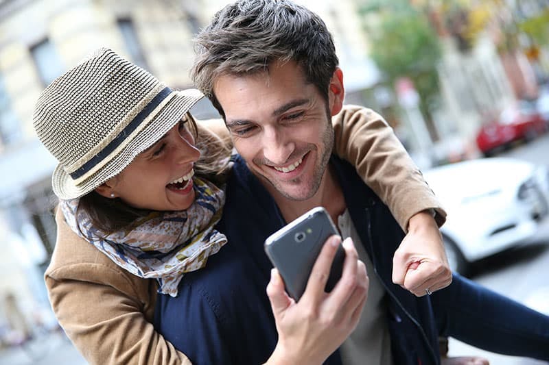 Lyckligt par som tittar i en mobiltelefon 